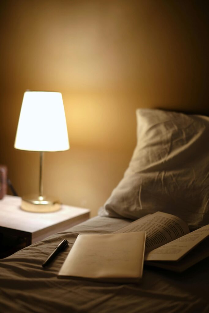 Warm bedside scene with open books, lamp, and a pillow, perfect for reading nights.